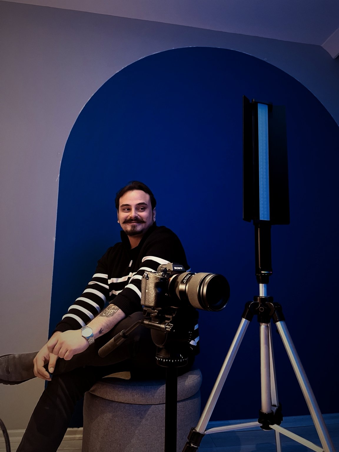 Doğan Özhan in the studio beside a cinema camera on a tripod
